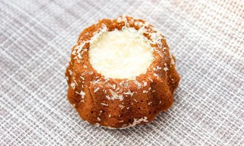 A round cake with a white souffle on the table, sprinkled with coconut chips Foto stock