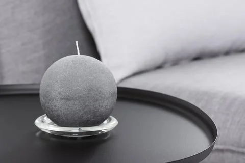 Round candle on a black table on the background of a sofa Stock Photos
