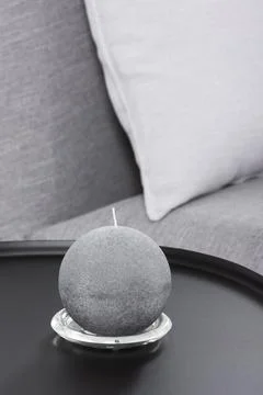 Round candle on a black table on the background of a sofa Stock Photos