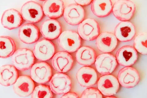 Round candy with a heart pattern lie on a paper background as a texture and a Stock Photos