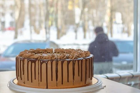 Round chocolate cake on a table in a cafe on the background of a window near the Stock Photos