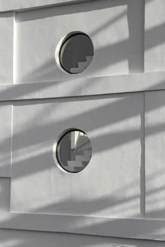 Round circle shaped windows on a white painted building with sunset shadow .. Stock Photos