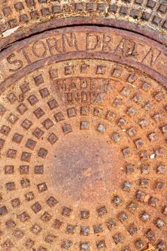 Round circular pattern of squares, rust orange storm drain cover, words storm Stock Photos