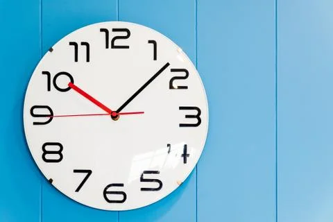 A round clock hanging on the wall of blue wood. Stock Photos