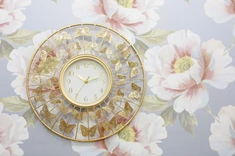 The round clock on the wall is stylized with butterflies. Stock Photos