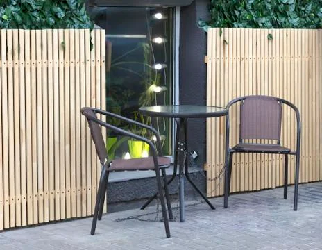 Round coffee table and two chairs stand on the street, waiting for visitors Stock Photos
