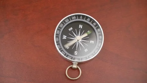 Round compass on wooden table with rotating pointer. Stock Footage 269895207