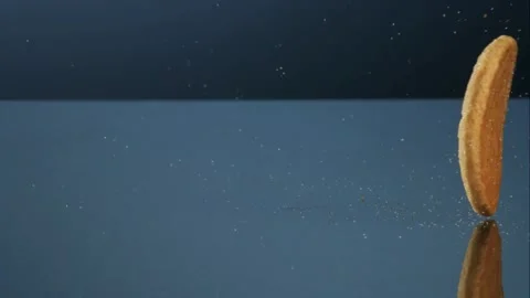 Round cookie falling and bouncing on a blue Stock Footage 327789623