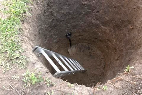 Round deep pit with a ladder. Digging pits. Stock Photos