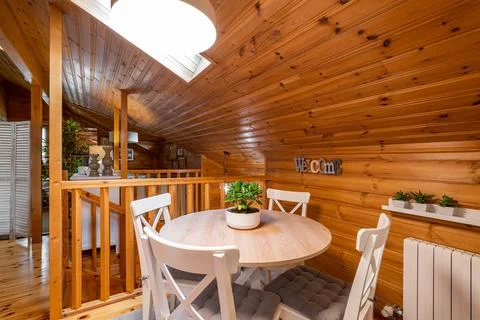 Round dining table with chairs on the second floor of completely wooden house Stock Photos