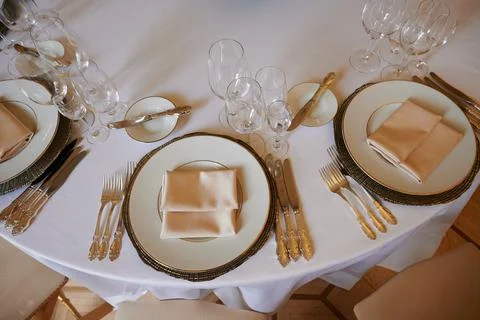 A round dining table with a white tablecloth and cloth napkins is prepared for a Stock Photos
