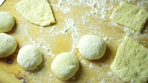 Round donuts and square blanks for donuts on a board sprinkled with flour Stock Footage 220449745