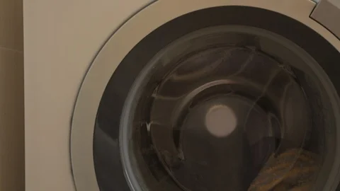 Round door of white washing machine works and turns with colored clothes. Was Stock Footage 93534645