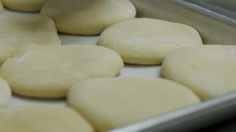 Round dough pieces get placed on tray to rise Stock Footage 93375894