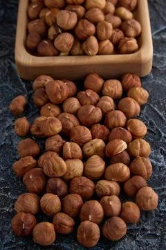 Round dried hazelnuts randomly placed on a textured gray background Stock Photos