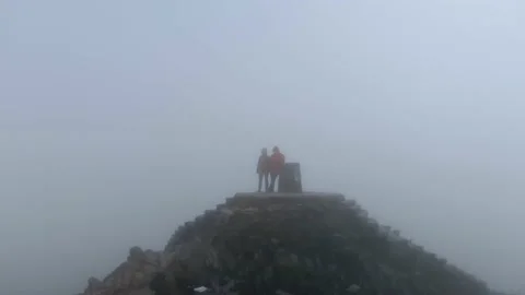 A round drone shot of a couple standing on the top of mountain Stock-Footage 146239678