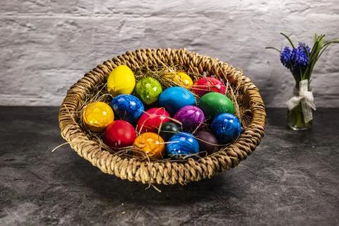 Round easter basket with colorful easter eggs Stock Photos