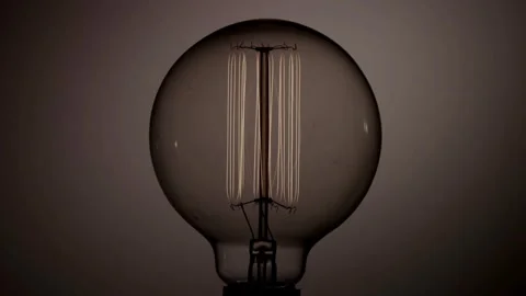 Round edison light bulb filament glows and dims slowly Stock Footage 329657280