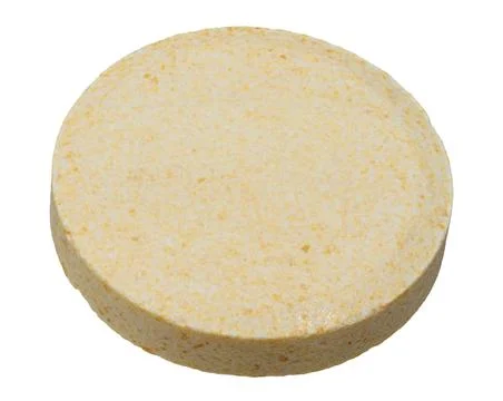 A round, flat, light yellow tablet with specks on an isolated background Stock Photos
