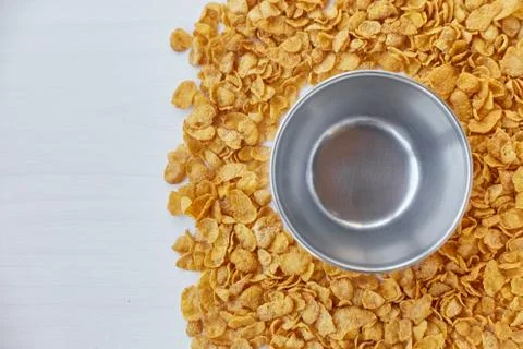 Round frame with empty metal bowl lined with corn flakes. Cornflakes scattered Stock Photos