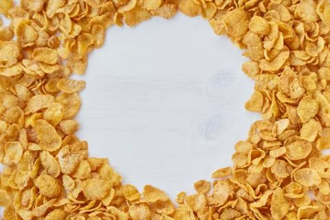 Round frame lined with corn flakes. Cornflakes scattered on a wooden table. Stock Photos