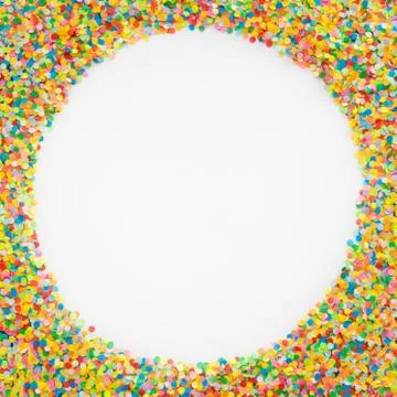 Round frame made of colored confetti. White background. Festive confetti. Stock Photos