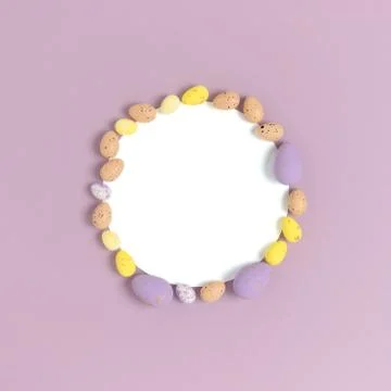 Round frame made of easter colorful eggs on a purple pastel background. Stock Photos