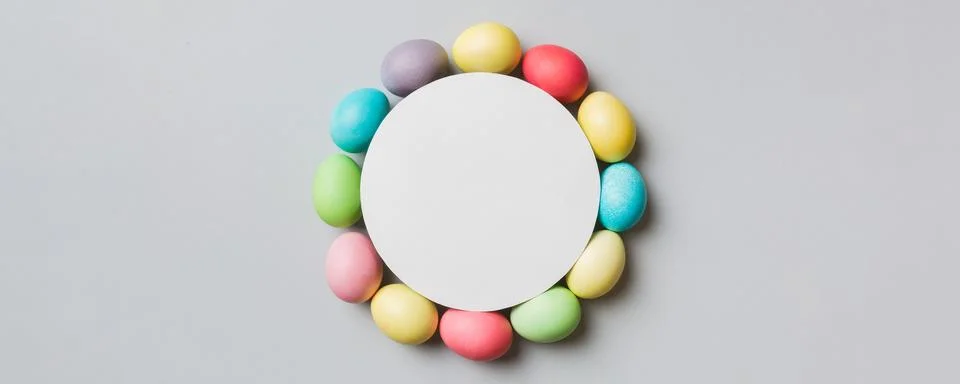 Round frame multicolored Easter eggs with white blank paper on a brown back.. Stock Photos