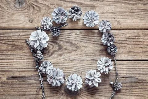 Round frame of white pine cones on a old wooden  table. Christmas background. Stock Photos