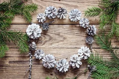 Round frame of white pine cones with fir branches on a old wooden  table. Chr Stock Photos