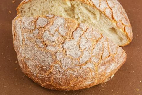 Round fresh white bread cut into two pieces is on a brown background Stock Photos