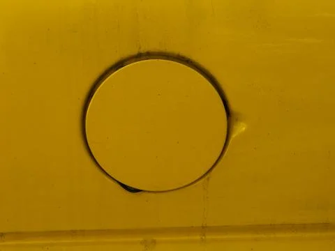 A round fuel cap access panel on a yellow vehicle. Foto stock