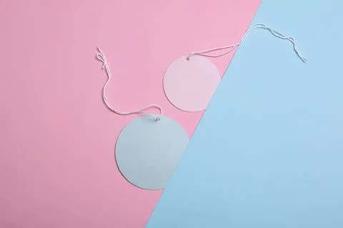 Round gift tags with strings on pink and blue background Stock Photos