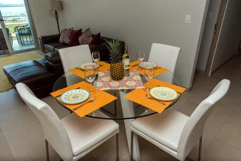 Round glass dining table set with colorful placemats Stock Photos