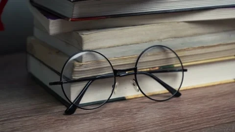Round glasses lie by a stack of books Stock Footage 168203954