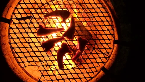 Round glowing fire pit with juicy lamb chops being grilled over coals Stock-Footage 339071567