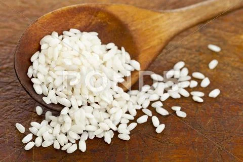 Round Grain Rice On A Wooden Spoon And A Wooden Surface