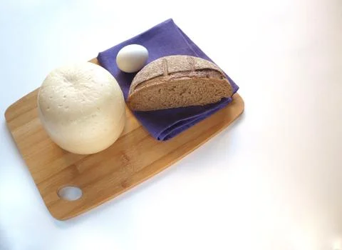 Round head of cheese with rustic fresh bread on a wooden tray. Stock Photos