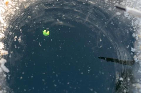 Round ice in the ice with a float on the line. Stock Photos