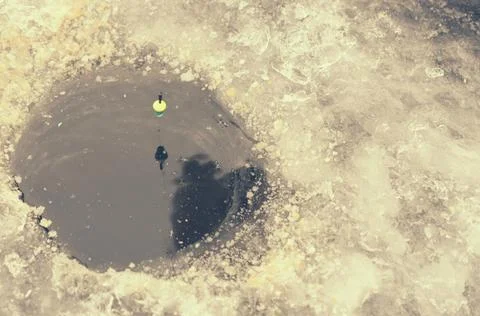Round ice in the ice with a float on the line. Stock Photos