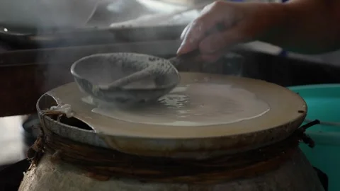 Round layer of rice batter cooks on a steaming plate while heat rises in a kitch Stock Footage 338000748