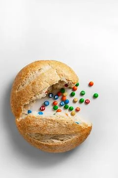 A round loaf of bread broken in half, vitamins are poured out of it. Stock Photos