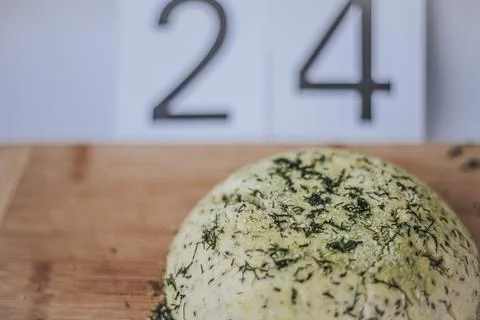 Round loaf of bread topped with herbs and spices on a wooden cutting board .. Stock Photos
