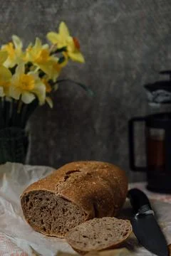 A round loaf of a crusty bread, on a rustic wooden table with scattered flour Stock Photos