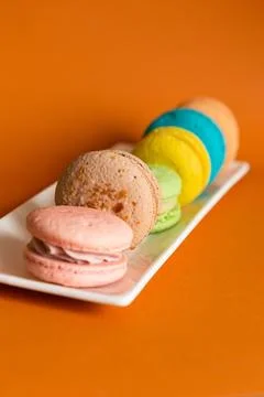 Round macaroons of different colors on an oblong rectangular white plate Photos