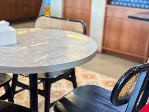 Round Marble Dining Table with Elegant Rattan Chairs on Patterned Tile Floor Stock Photos