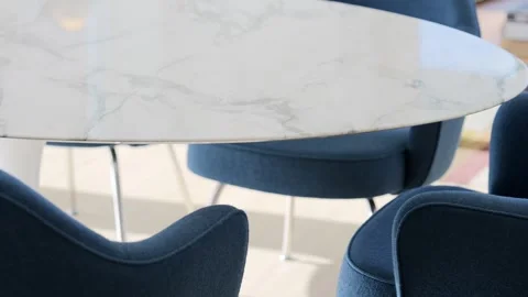 Round marble dining table surrounded with comfy blue armchairs in modern Stock Footage 243517294