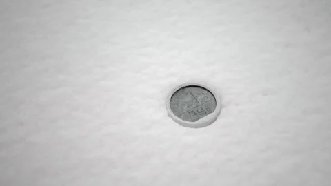 A round metal marker visible through a hole in fresh white snow on a cold day Video stock 331719664