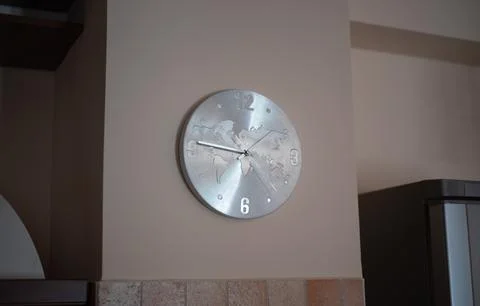 Round metallic wall clock featuring an engraved world map on beige wall Stock Photos