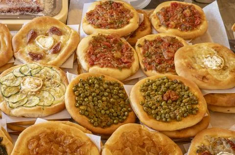 Round mini pizzas topped with red peppers, green peas, caramelized onions, .. 库存照片